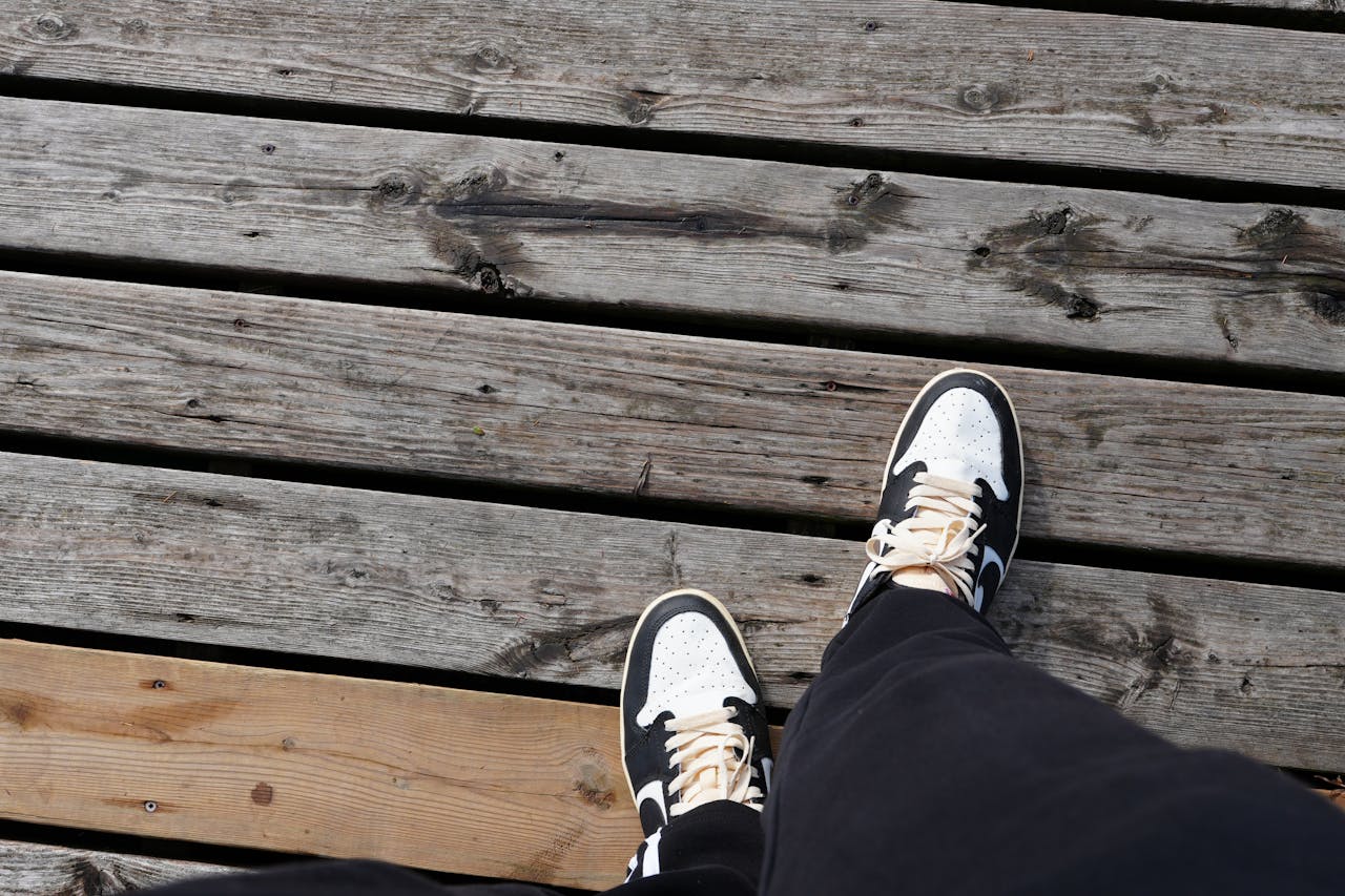 Black and white sneakers on weathered wooden planks, capturing a casual outdoor vibe.