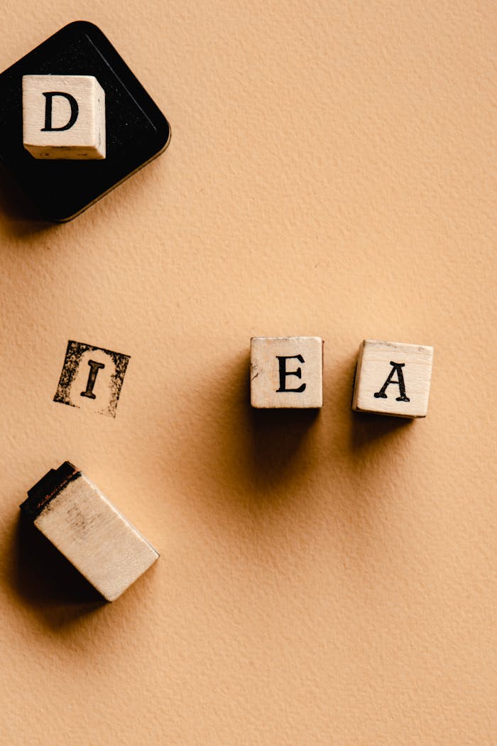 Wooden letter stamps arranged to spell 'IDEA' on a beige surface. Perfect for creative concepts.